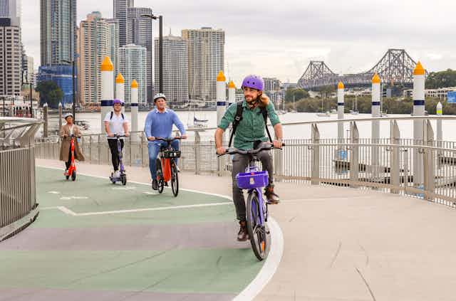 Riders on e-bikes and e-scooters travelling over a city bridge