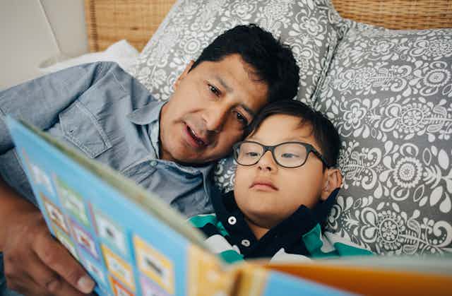 father and son do shared book reading on bed