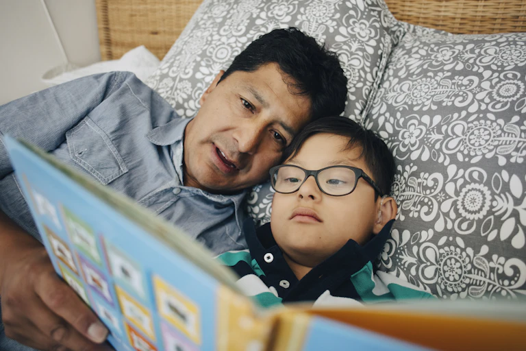 father and son do shared book reading on bed