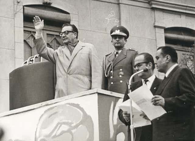 Salvador Allende sobre una palestra levanta la mano.