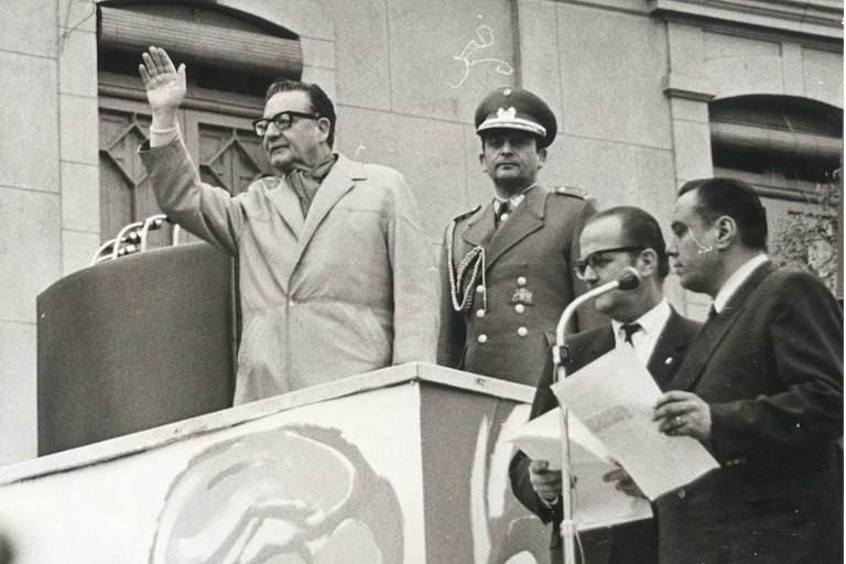 Salvador Allende sobre una palestra levanta la mano.