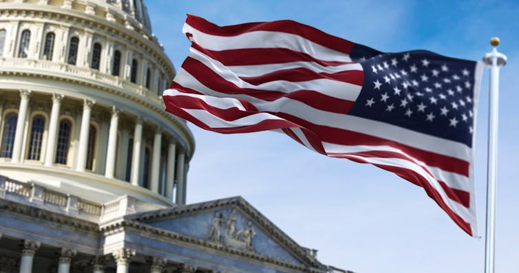 A US flag flying in front of the US Capitol building.