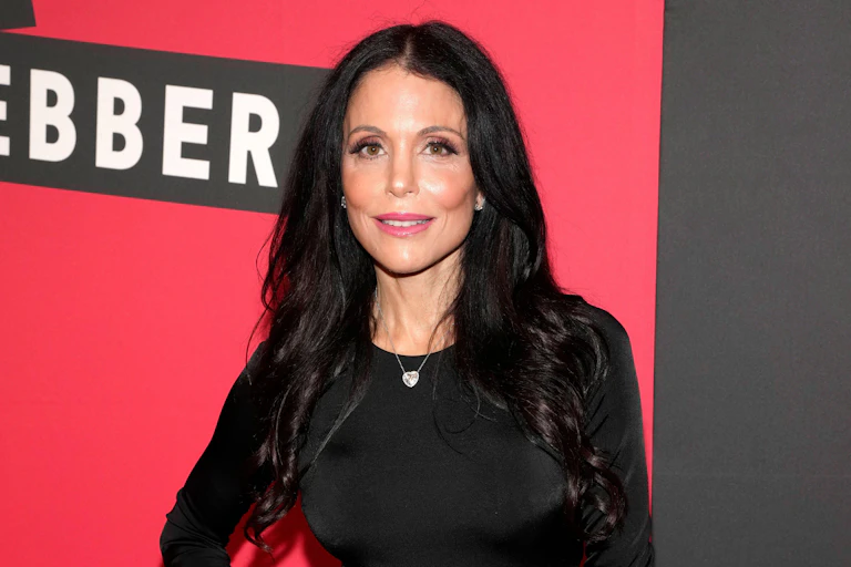 TV star Bethany Frankel wearing black in front of a red and black background.