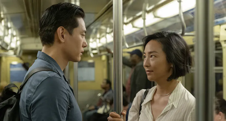 Nora and Hae Sung on the metro staring at each other.