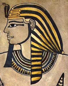 A side on portrait of an Egyptian pharaoh wearing a gold hat and eyeliner.