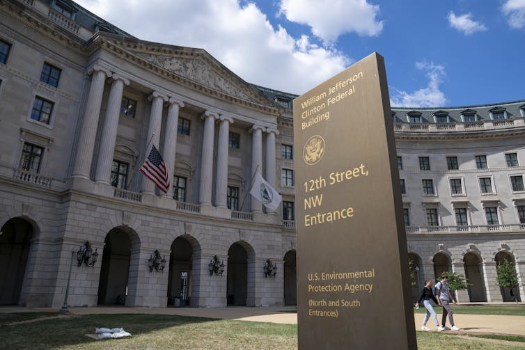 A large granite building with a sign in front of it.