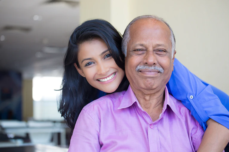 A young South Asian woman and older South Asian man pose for a photo.