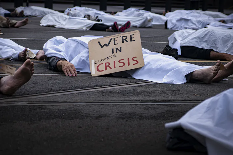 Protesters lie down covered in a sheet.