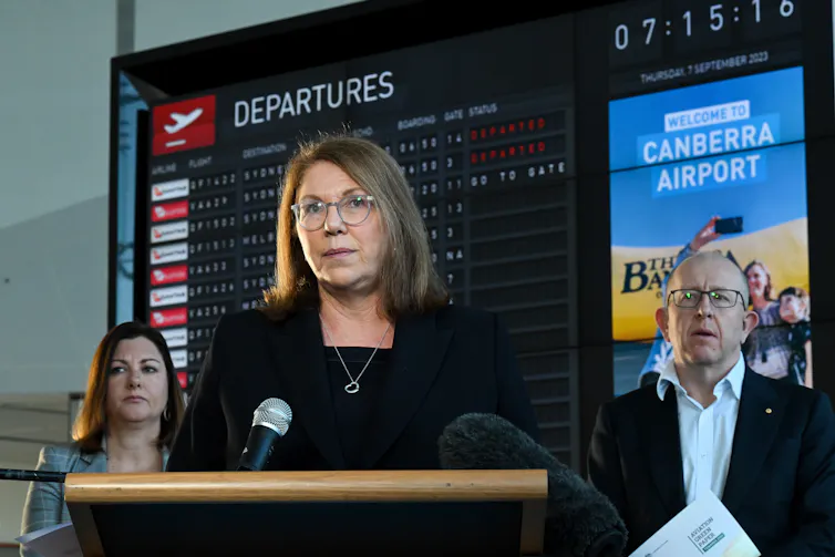 Woman gives speech in front of airport departure signs