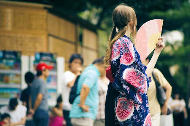 Woman wearing a yukata holding hand fan.
