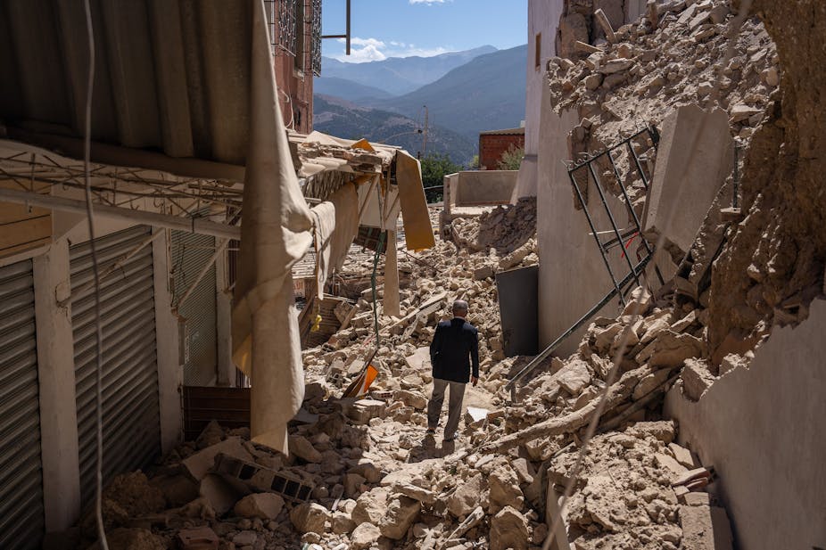 A man walks among the rubble of collapsed buildings