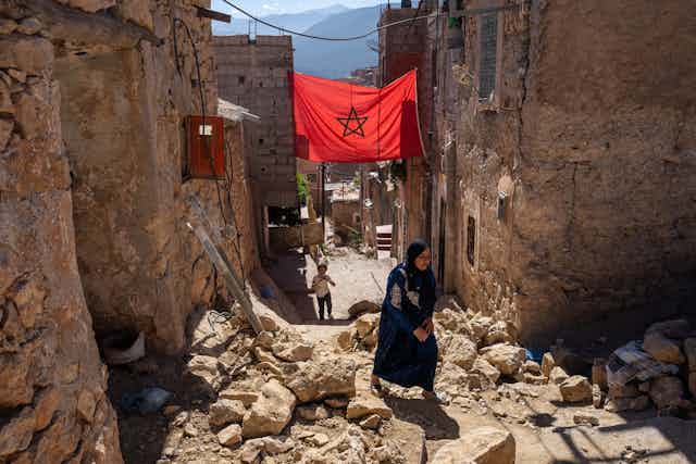 A woman walks past the rubble of damaged buildings 