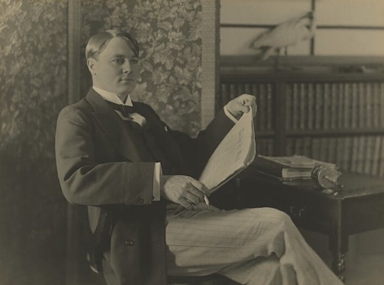 Sepia photo of a gentleman reading a newspaper in 1896.