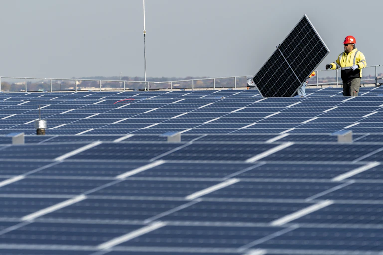 A construction worker installs a solar panel on a huge roof
