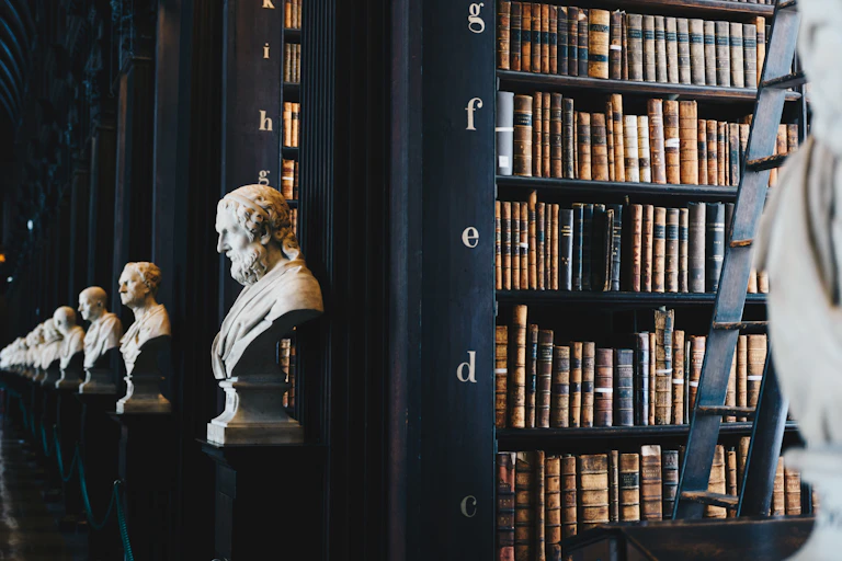 Busts of male heads on the end of rows of library books.