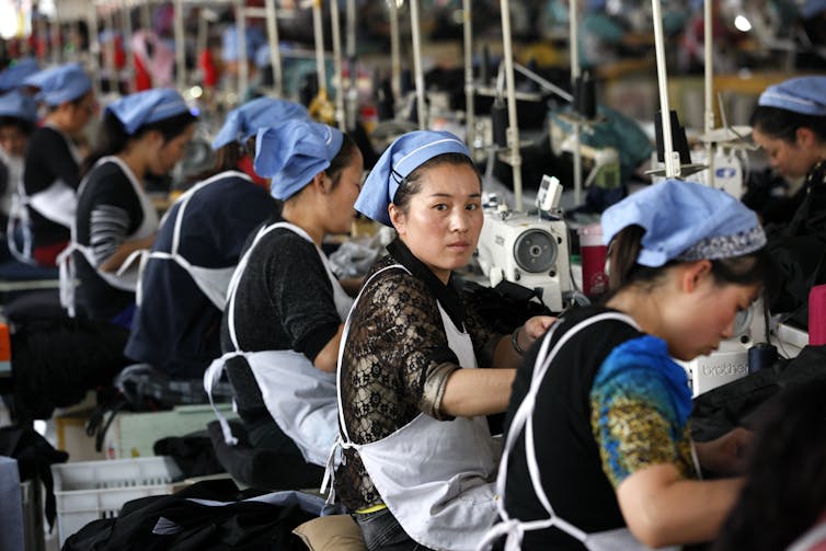 A worker in a cloth factory assembly line turns to look at the camera.