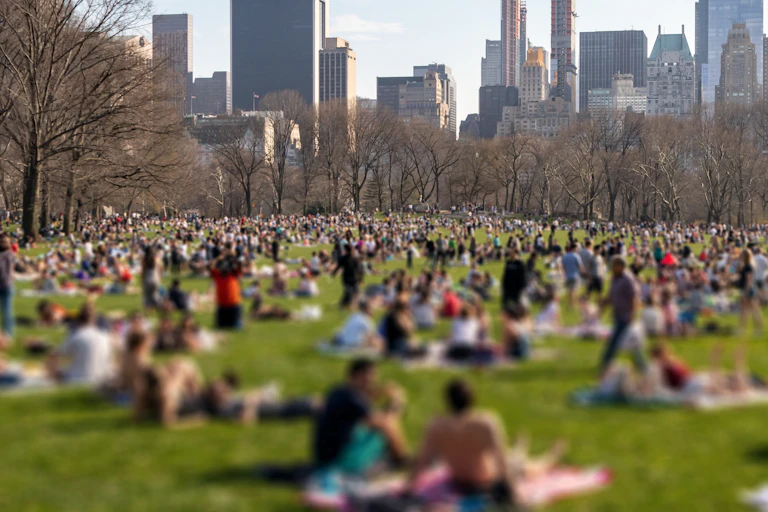 blurry image of people relaxing on grass in a city park
