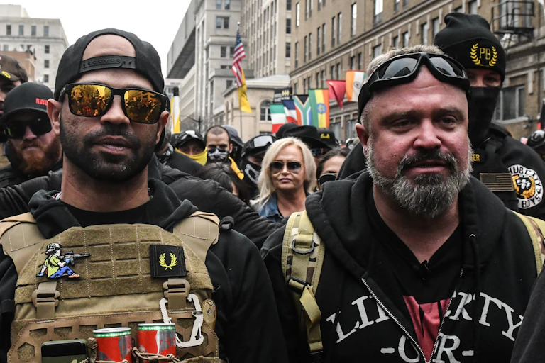 Two men stand on a crowded street.