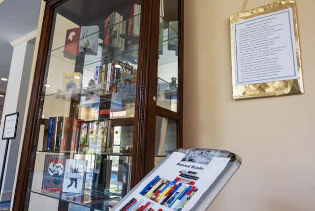 A glass-fronted book case shows various titles