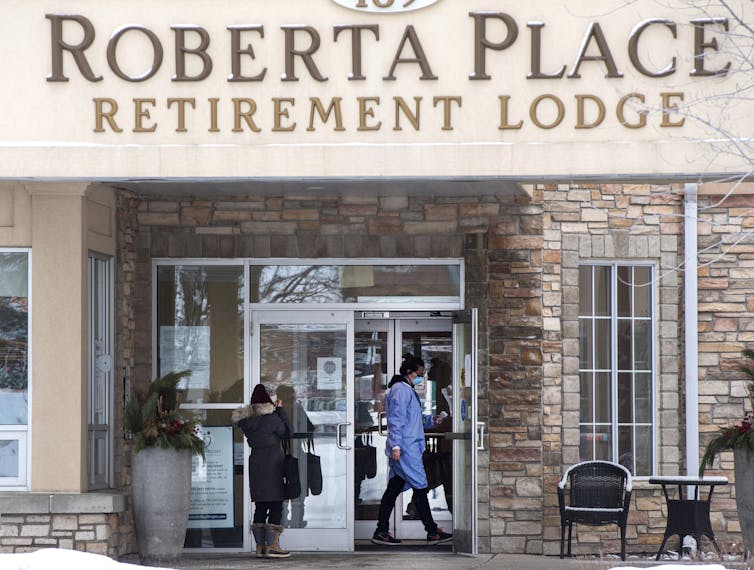 A person walks towards the glass-front door of a building that says 'Roberta Place Retirement Lodge' across the front