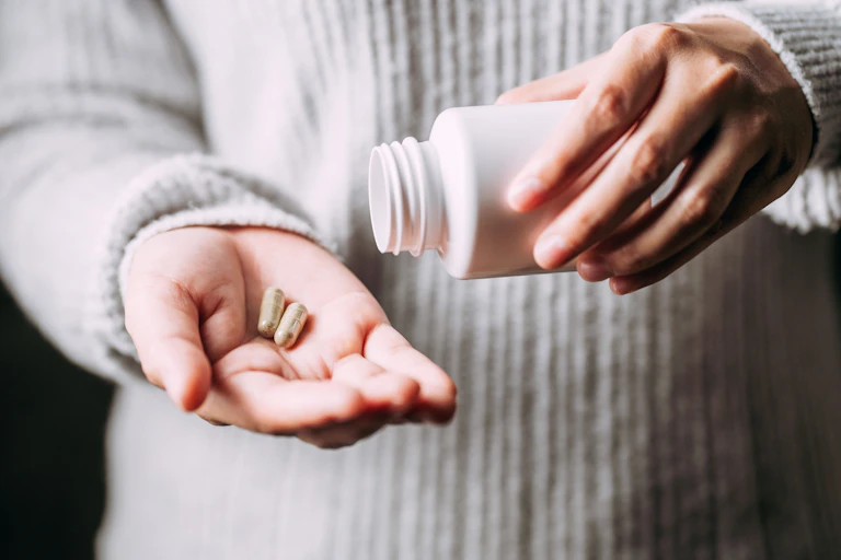 woman's hands with two capsules in one