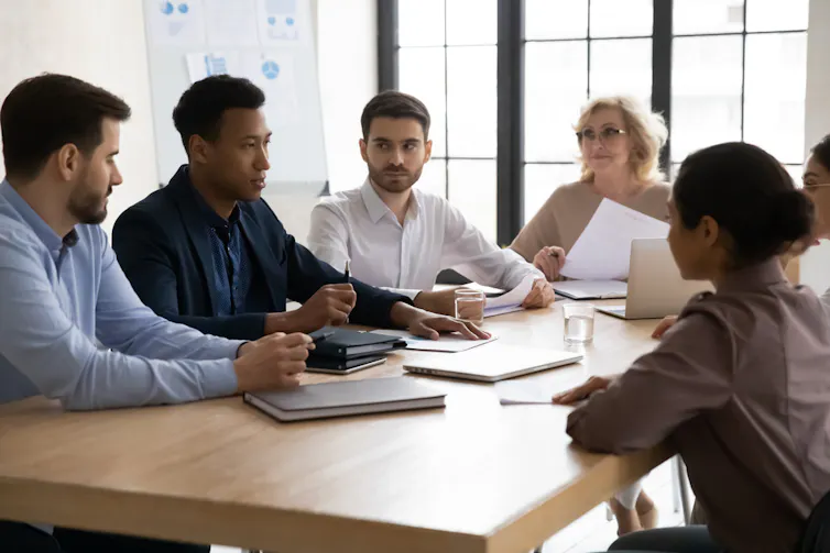 Staff members sit round a table and discuss work.