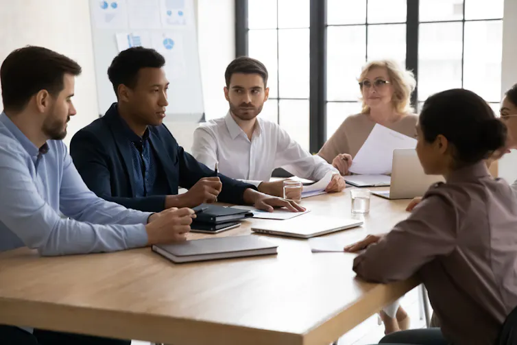 Staff members sit round a table and discuss work.