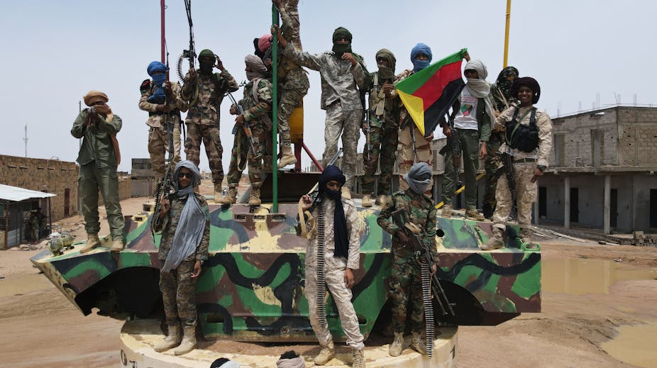 Des militaires armés en treillis sur un char, avec un drapeau de l'Azawad