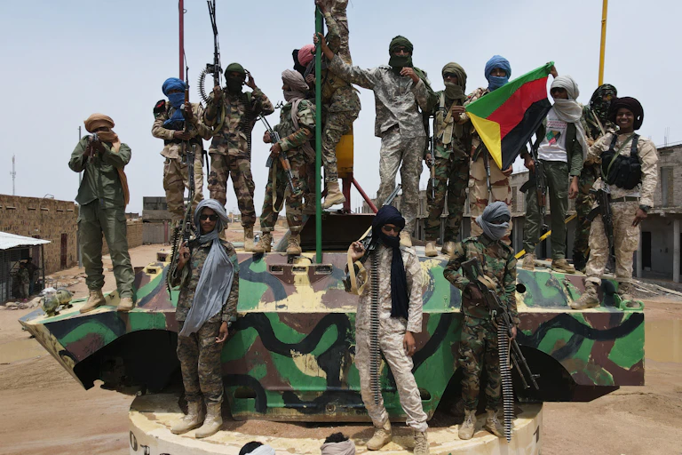 Des militaires armés en treillis sur un char, avec un drapeau de l'Azawad