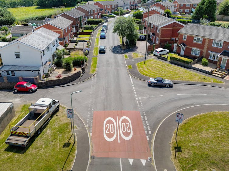 An aerial view of a residential street with 20 painted on the road in bold numbers.