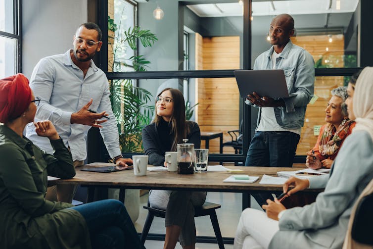 A diverse group of people having a conversation around a table in an office