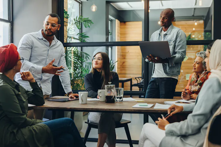 A diverse group of people having a conversation around a table in an office