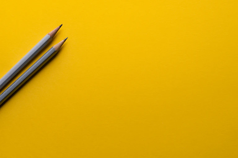 Two lead pencils on yellow background