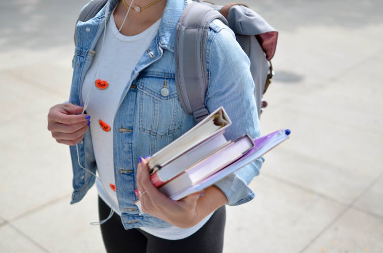 A student carries a stack of books.