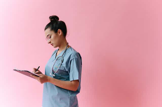 A nurse writes on a clipboard