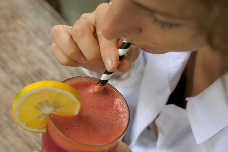 Photo d’une femme buvant un smoothie grâce à une paille en carton.