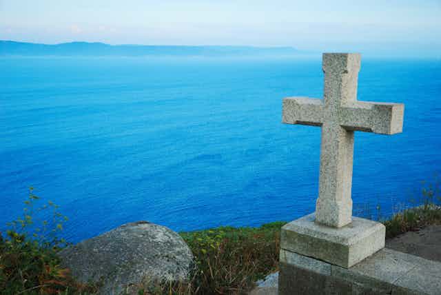 A stone cross on a cliff overlooking the Atlantic Ocean.