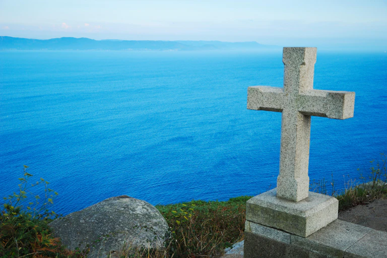 A stone cross on a cliff overlooking the Atlantic Ocean.
