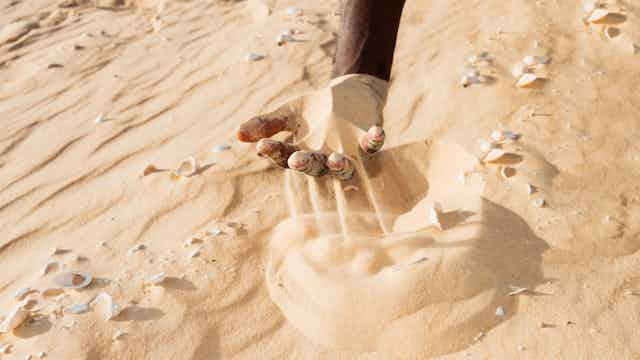 A hand sifting sand