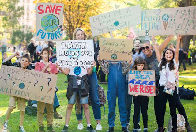 Des enfants entourés de leurs parents brandissent des pancartes où l'on peut lire des slogans s'insurgeant contre le dérèglement climatique 