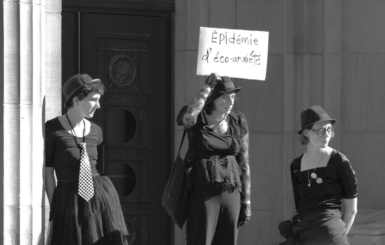groep demonstranten die een bord omhoog houden met de tekst ‘eco-angstepidemie’