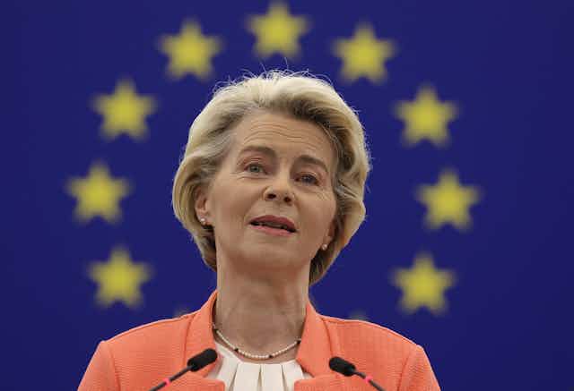 Ursula von der Leyen standing in front of an EU flag. 