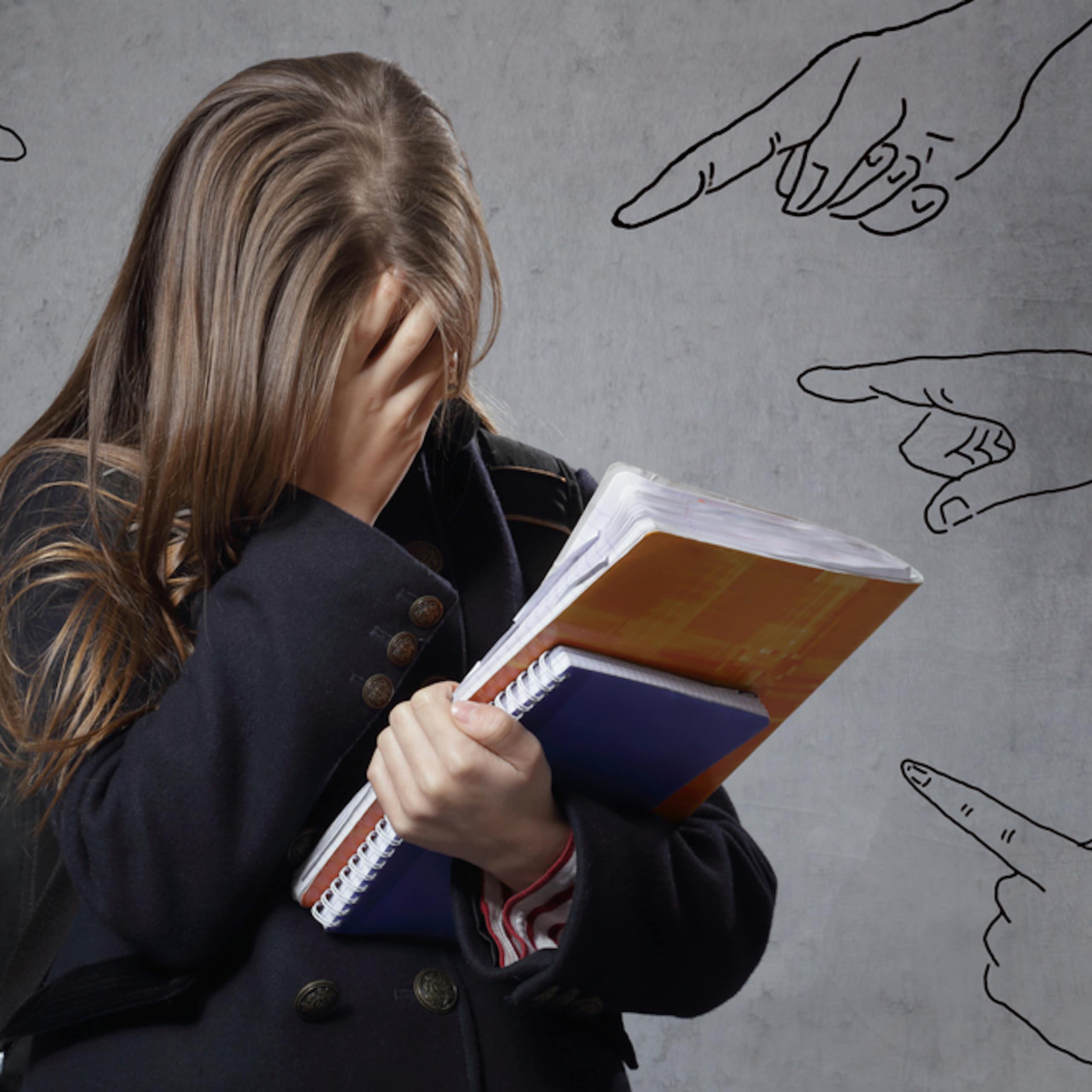 Adolescente solitaire en pleurs  avec des dessins de doigts pointés symbolisant le harcèlement