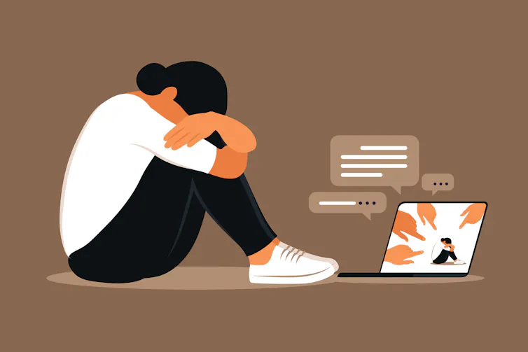 Femme déprimée assise par terre face à un ordinateur et victime de cyberharcèlement