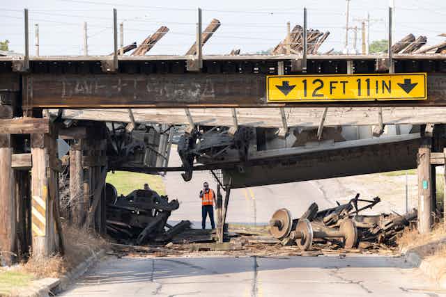 A collapsed bridge and debris is seen above a clean-up worker in North Sioux City, S.D