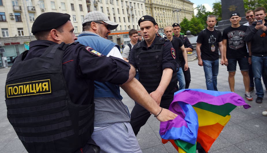 Des policiers russes arrêtent un homme tenant un drapeau aux couleurs de l'arc-en-ciel