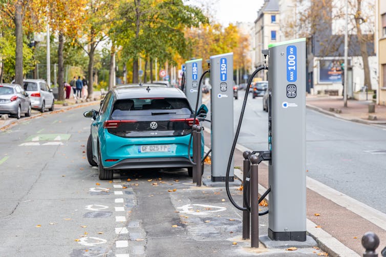 An electric car plugged into a charger in a French street.