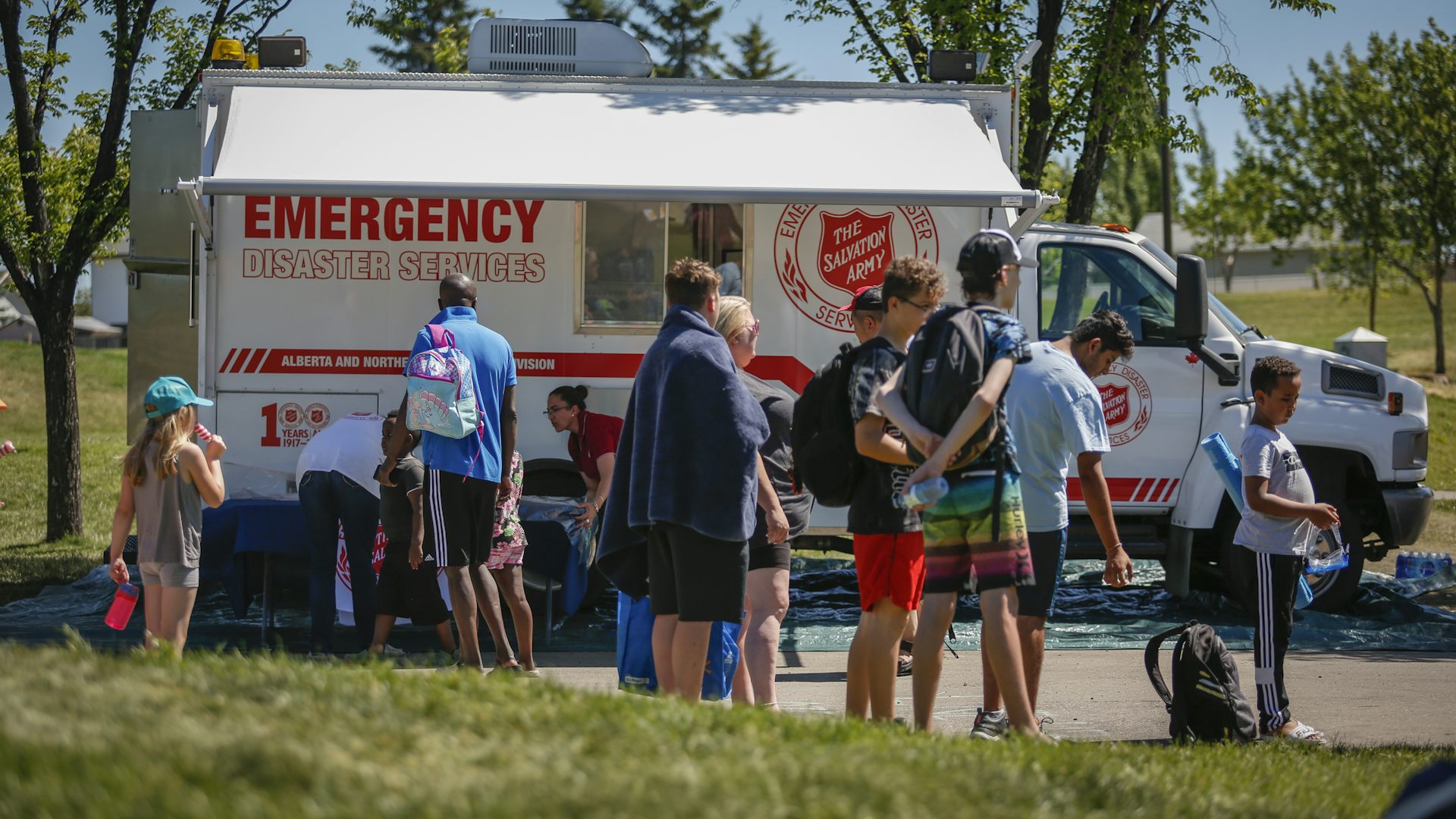 People stand around an emergency vehicle outside in the summer