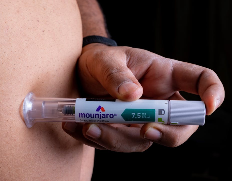A person injects a vial of Mounjaro into his abdomen.