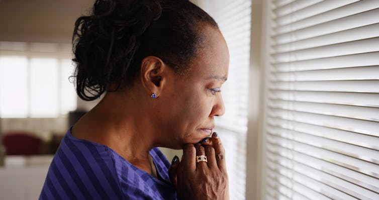 Woman looking sadly out of window.